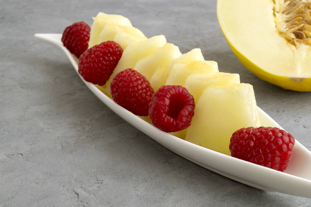 Summer fresh snack, melon and raspberry in a glass bowl. - Photo, Image