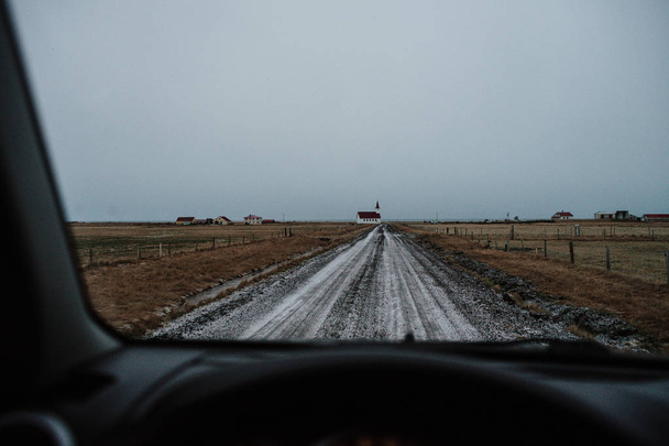 Rijden op een rechte weg van vuil naar een kerk in IJsland - Foto, afbeelding