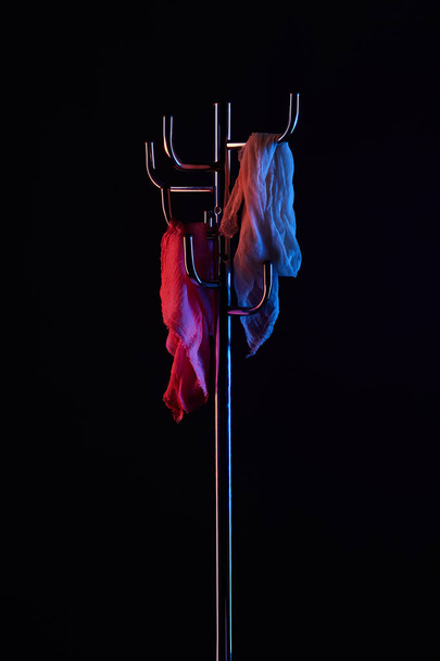 шарф висит на вешалке пальто под тонированным светом изолированы на черный
 - Фото, изображение