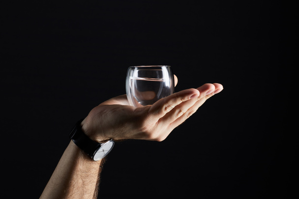 cropped shot of man holding glass of liquid isolated on black - 写真・画像