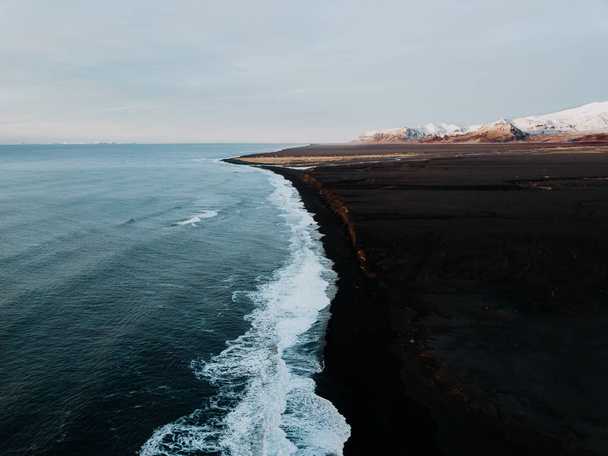 La costa dell'Islanda con una spiaggia di sabbia nera e alcune montagne sullo sfondo, fotografato da un drone
 - Foto, immagini