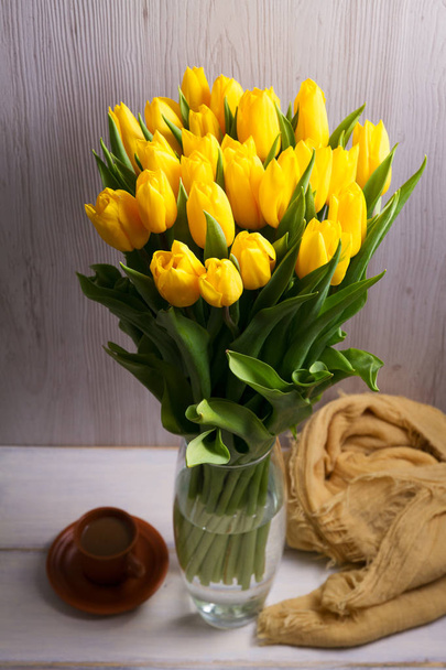 Bouquet of spring tulips flowers in vase on white wooden background. Yellow tulips - Foto, immagini