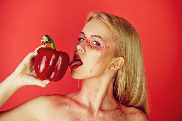 girl with creative fashionable makeup lick bell pepper - Foto, Imagen
