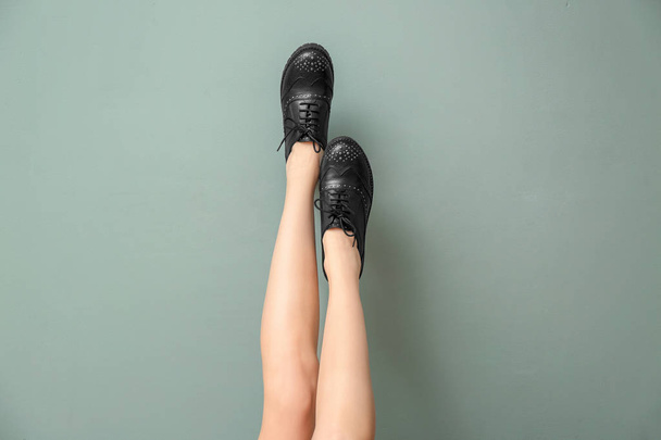 Legs of young woman in stylish casual shoes on color background - Фото, зображення