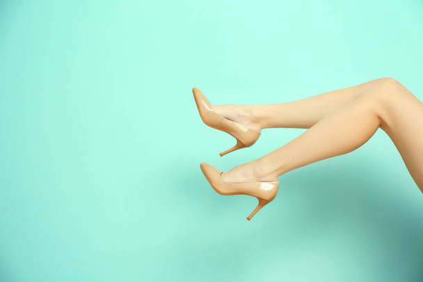 Legs of young woman in elegant shoes on color background - Foto, Imagem