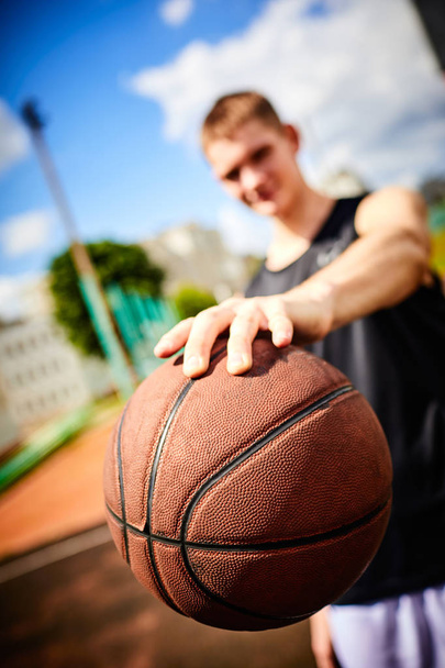 человек держит мяч во время игры в баскетбол на открытом воздухе
 - Фото, изображение