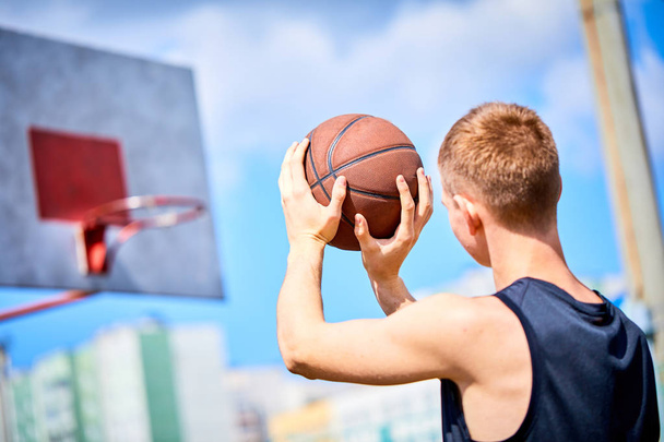 mies pitää palloa pelatessaan koripalloa ulkona
 - Valokuva, kuva