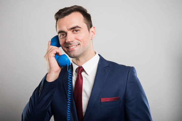 Houkutteleva liikemies puhuu sininen puhelin vastaanotin
 - Valokuva, kuva