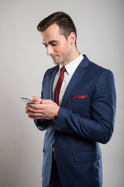 Atractivo hombre de negocios mensajes de texto en el teléfono inteligente
 - Foto, imagen