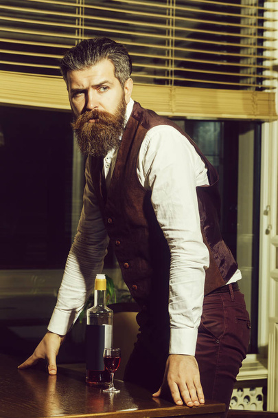 Hipster standing at table with bottle and glass of wine - Foto, afbeelding