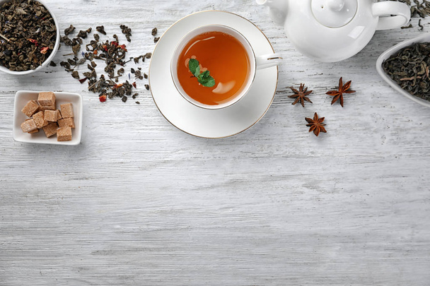 Feuilles de thé vert sèches et tasse de boisson aromatique sur la table
 - Photo, image