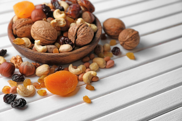 Plate with different nuts and dried fruits on wooden table - Foto, imagen
