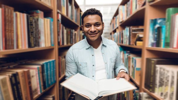 Ethnic indian mixed race student in library surrounded by books - Foto, Bild