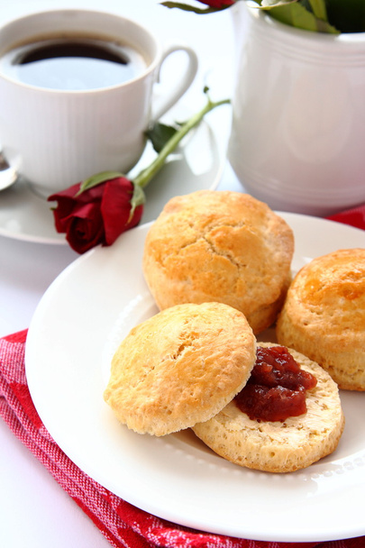 zelfgemaakte scones met aardbeienjam en een kopje thee - Foto, afbeelding