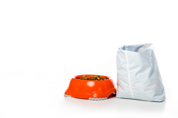 vista de cerca del tazón de plástico y la bolsa con alimentos para animales aislados en blanco
 - Foto, Imagen
