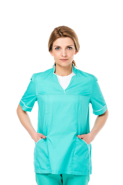 beautiful young veterinarian standing with hands in pockets and looking at camera isolated on white - Фото, зображення