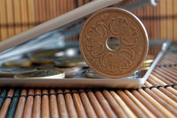 Куча датских монет номиналом в пять крон (корона) в зеркале отражают бумажник лежит на деревянном бамбуковом фоне - задней стороне
 - Фото, изображение