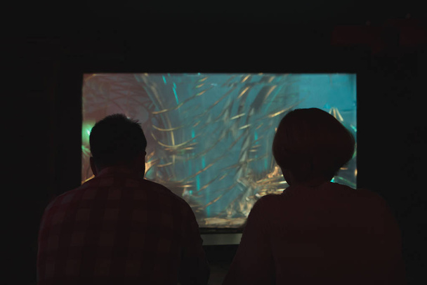 Silueta mladého páru na pozadí projekce s hrou. Muž a dívka hrát video hry v noci - Fotografie, Obrázek