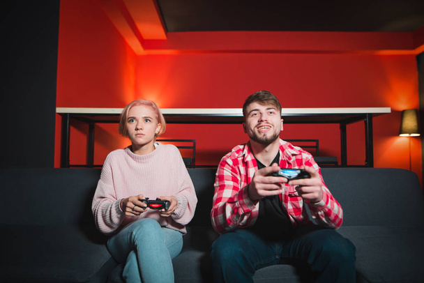 Una pareja juega el juego en la consola. Un hombre sonriente está triste. Un hombre gana a una mujer en un videojuego
 - Foto, imagen