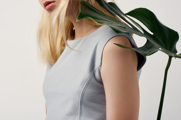 cropped shot of attractive young woman with monstera leaf on shoulder isolated on white - Valokuva, kuva
