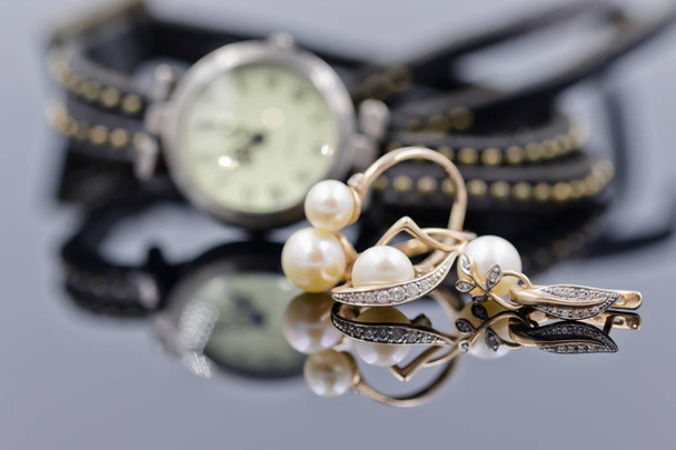 Orecchini in oro con perla sullo sfondo di orologi
 - Foto, immagini