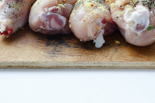 Chicken drumsticks on a wooden board. On white, isolated background.Top view. Flat lay. - Foto, afbeelding