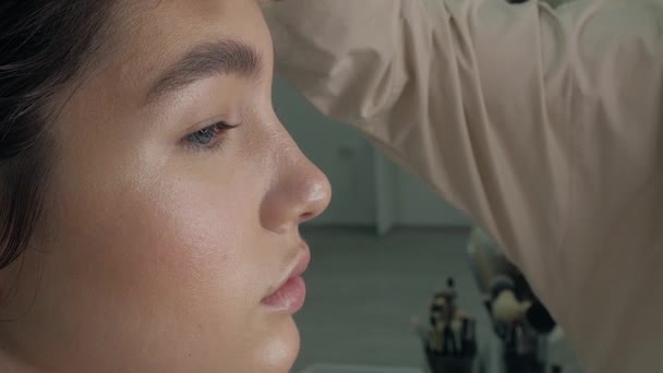 Young beautiful woman applying make-up by make-up artist - Filmagem, Vídeo