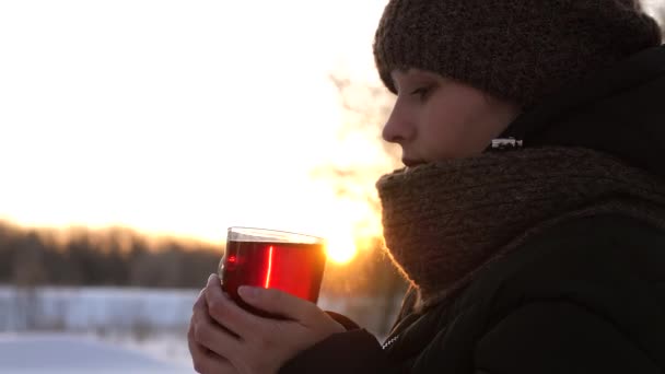 Όμορφο κορίτσι στέκεται στο ηλιοβασίλεμα με ζεστή κούπα τσάι και γέλιο. - Πλάνα, βίντεο