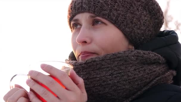 Mooi bevroren meisje het drinken van thee van transparant glas in open lucht. - Video