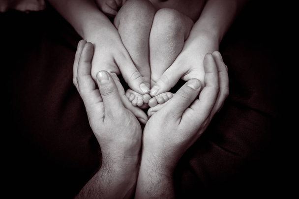 Las manos de papá sobre las manos de su madre y los pies de bebé. Concepto de familia feliz. Hermosa imagen conceptual de la maternidad
 - Foto, Imagen