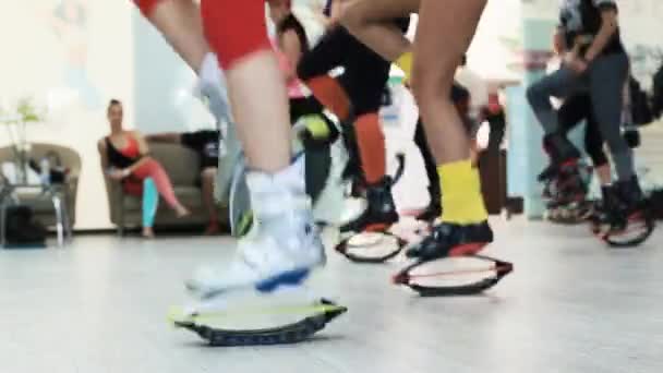 Grupo de jovens mulheres caucasianas desportivas fazendo exercícios de fitnes com kangoo salta sapatos em um ginásio
. - Filmagem, Vídeo