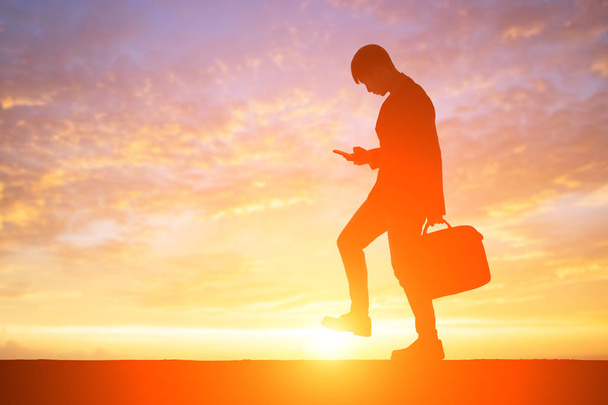 silhouette d'homme d'affaires utilisant le téléphone au coucher du soleil
 - Photo, image
