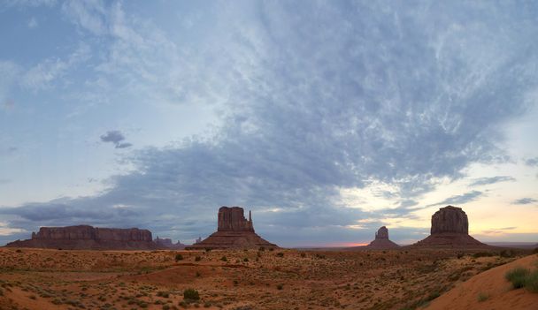 Monument vue sur la vallée au coucher du soleil avec un ciel nuageux merveilleux et des lumières sur les mitaines
 - Photo, image