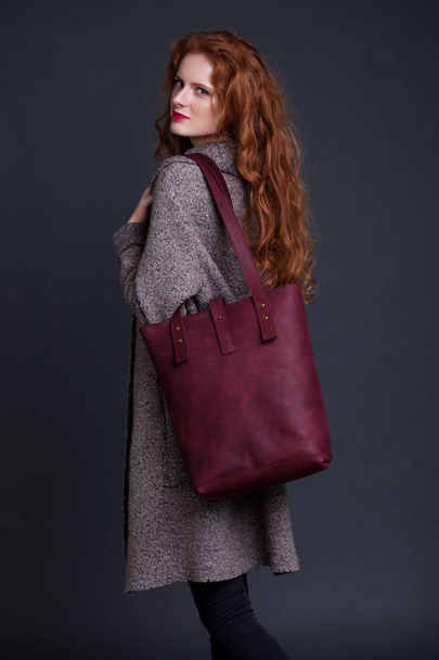 Red hair fashion model holding large leather bag  - Foto, afbeelding