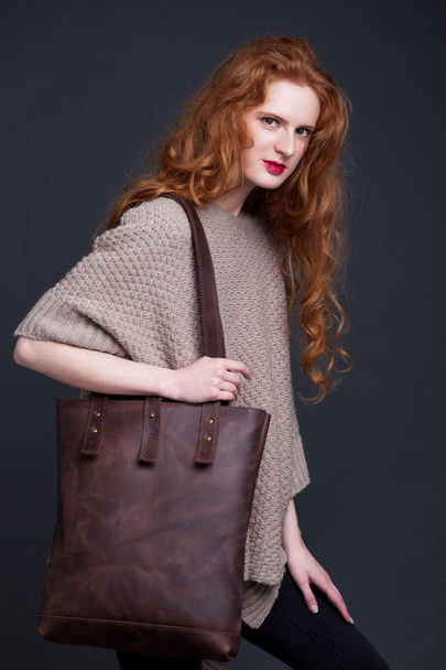 Red hair fashion model holding large leather bag  - Valokuva, kuva