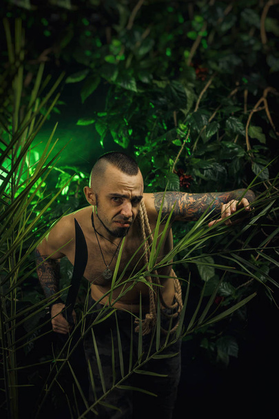 um homem na selva com facões atacando o inimigo
 - Foto, Imagem