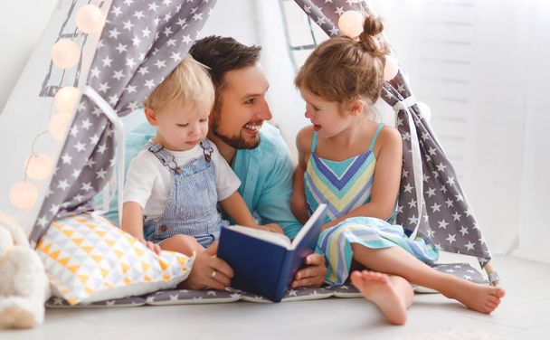 family father reading to children book in tent at home - Valokuva, kuva