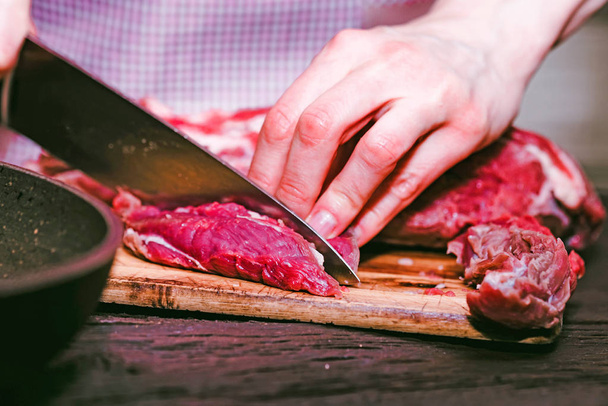 Las manos femeninas cortan carne cruda cerca
 - Foto, Imagen