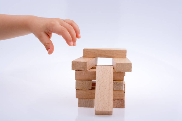 Hand playing with wooden building blocks on white background - Photo, Image