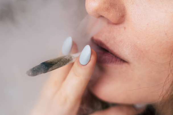 女性を吸う大麻雑草、共同および彼の手でライター。黒の背景にたばこを吸います。医療マリファナの使用と大麻の合法化の概念. - 写真・画像