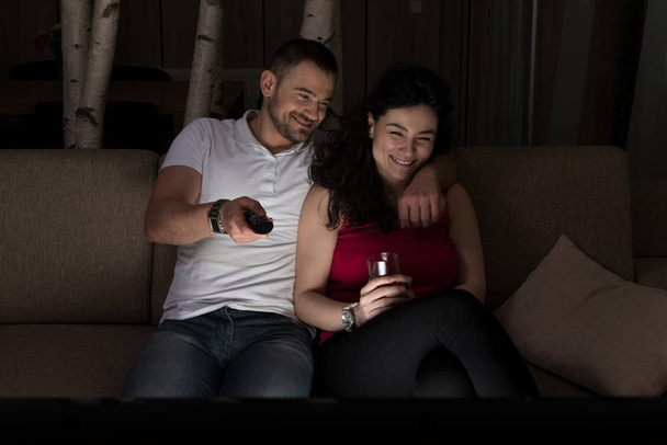 Young Heterosexual Couple Hugging on Sofa and Watching Movie on Tv at Home - Foto, Imagem