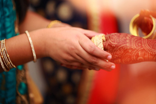 noivo coloca pulseira na mão da noiva na cerimônia de pulseira com luzes
. - Foto, Imagem