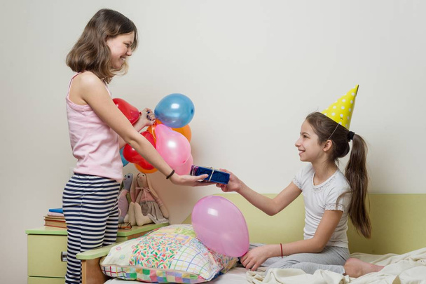 Birthday morning. Older sister giving surprise gift to her cute little sister. Children at home in bed - Φωτογραφία, εικόνα