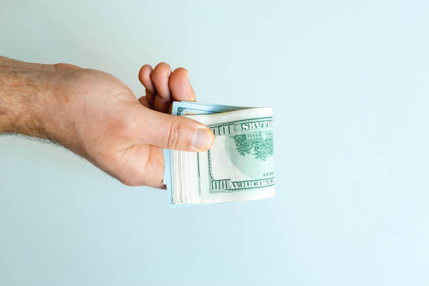 Χέρι των ανδρών με μεγάλη δέσμη των αμερικανικών δολαρίων σε άσπρο φόντο - Φωτογραφία, εικόνα