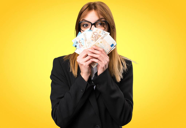 Young business woman taking a lot of money on colorful background - Photo, Image