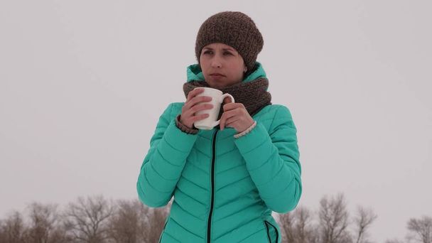 Ragazza congelata si riscalda con tazza calda nell'aria fresca gelida in inverno. Bevi il tè nel parco invernale. Caffè caldo
. - Foto, immagini
