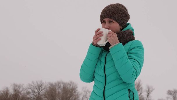 Ragazza congelata si riscalda con tazza calda nell'aria fresca gelida in inverno. Bevi il tè nel parco invernale. Caffè caldo
. - Foto, immagini