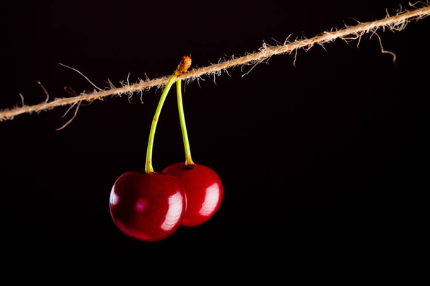 Cherry and rope on black with clamp - Zdjęcie, obraz