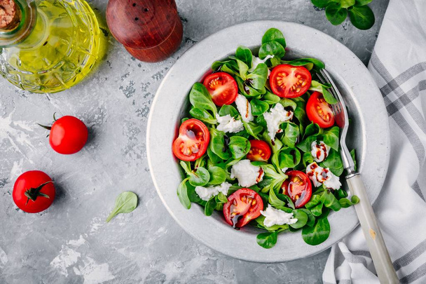 tuoretta salaattikulhoa vihreillä lehdillä, mozzarellalla, tomaateilla ja balsamikastikkeella
 - Valokuva, kuva