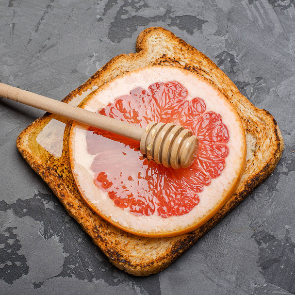 Toast on a gray background with a slice of grapefruit and honey - Fotoğraf, Görsel